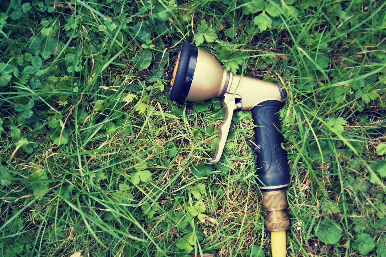 Giardiniere che spruzza diserbante naturale su un'aiuola fiorita.