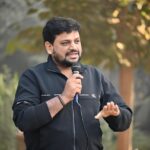 Immagine di un concorrente di Affari Tuoi con pacchi colorati sul tavolo durante il gioco.