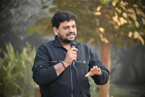 Immagine di un concorrente di Affari Tuoi con pacchi colorati sul tavolo durante il gioco.