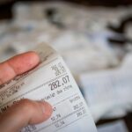 Giocatore felice mostra il biglietto vincente del Superenalotto con il numero 6 evidenziato.