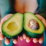 Avocado intero su un piatto, simbolo di un'alimentazione sana e discussione sui benefici e rischi.