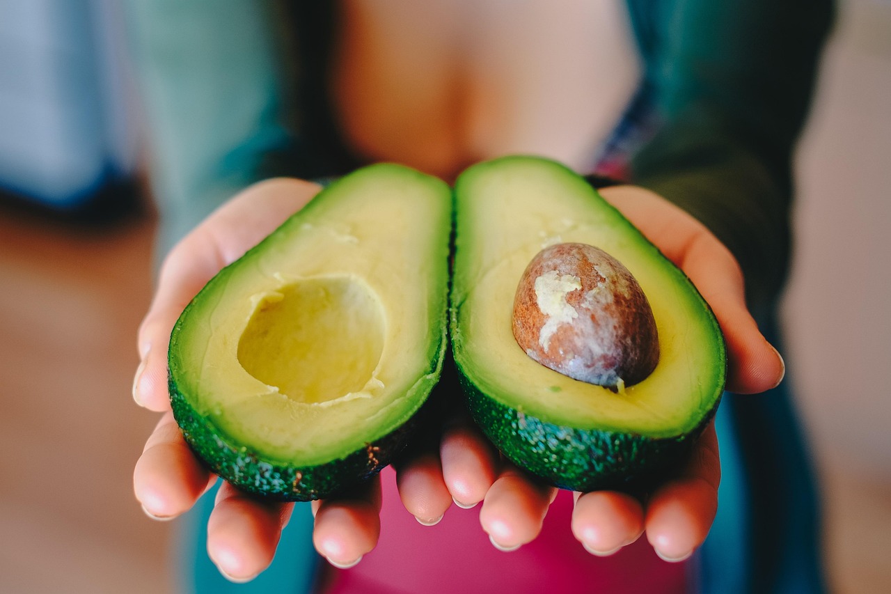 Avocado intero su un piatto, simbolo di un'alimentazione sana e discussione sui benefici e rischi.